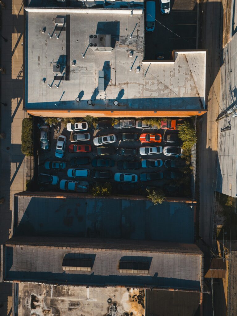 Aerial shot of a crowded urban parking lot filled with various cars.